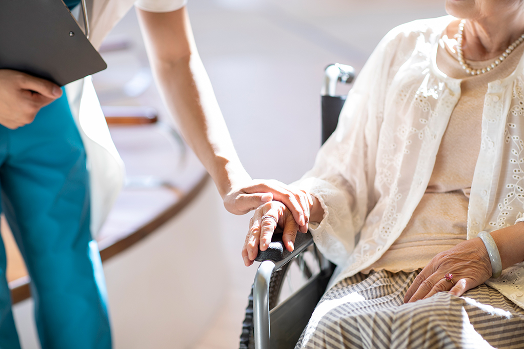 휠체어 탄 사람의 손을 잡는 사진