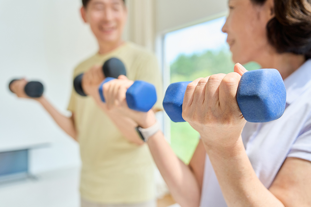 실내에서 아령을 들고 팔 운동을 하는 두 사람